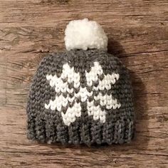 a gray and white knitted hat sitting on top of a wooden table