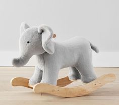 a stuffed elephant sitting on top of a wooden rocking toy