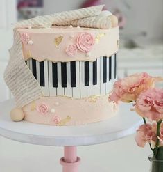 there is a cake that has been decorated with piano keys and pink carnations