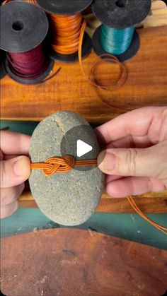 someone is making a rock with yarn and thread on it in front of some spools of thread