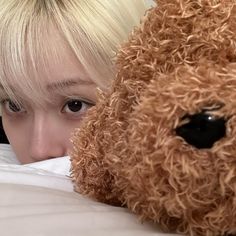 a person laying in bed with a stuffed animal on their chest and the head of a teddy bear behind them