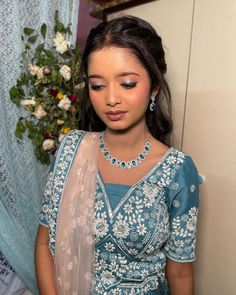 a woman wearing a blue and white outfit with flowers on the wall in the background