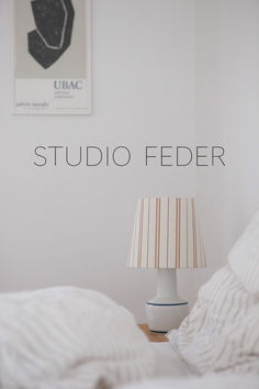 a lamp sitting on top of a bed next to a white wall with the words studio feeder above it