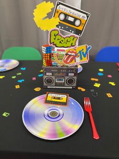 a table topped with a cd player next to a fork and knife on top of a black table cloth