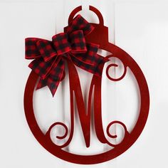 a red ornament with a bow hanging on the front door to hang it's monogrammed name