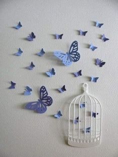 a white birdcage with blue butterflies flying out of it's cage on the wall