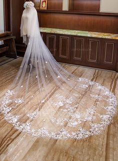 the bride is wearing a long veil with flowers on it