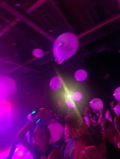 a group of people standing on top of a dance floor with balloons in the air