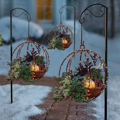 three metal balls with lights hanging from them in the snow