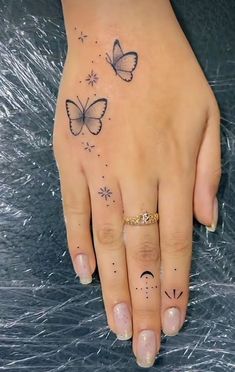 a woman's hand with two butterflies on her left and one butterfly on the right