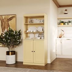 a yellow cabinet with dishes on it next to a potted plant