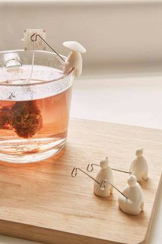 tea being poured into a glass cup with small figurines on the table next to it