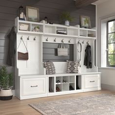 an entryway with white storage cabinets and hanging items on the wall, along with a rug in front of it