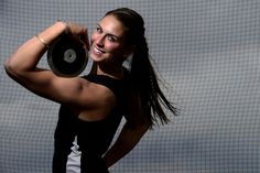 a woman is posing with her arms behind her head and holding a disc in front of her face