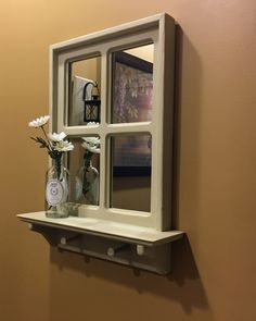 two vases with flowers sit on a shelf in front of a wall mounted mirror