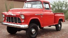 an old red truck parked in front of a building