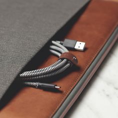 an open laptop computer case sitting on top of a white marble table next to a black and brown charger