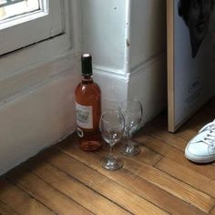 there is a bottle and two wine glasses on the floor next to a pair of shoes