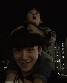 a man holding a child in the air at night