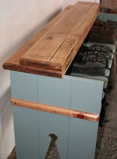 a wooden bench sitting in the middle of a room next to a wall with shoes on it