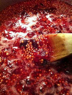 a wooden spoon stirring red sauce in a pot