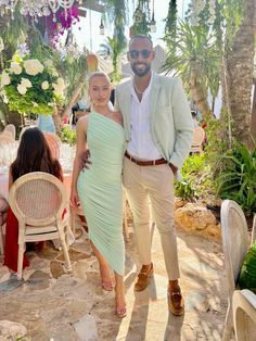 a man and woman standing next to each other in front of tables with flowers on them