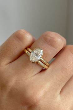 a woman's hand holding a gold ring with a pear shaped diamond on it