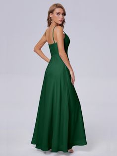 a woman in a long green dress is looking back at the camera with her hands on her hips