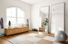 a large mirror sitting on top of a wooden floor next to a white ball and yoga mat