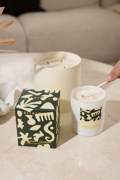 a candle sitting on top of a table next to a box with a spoon in it