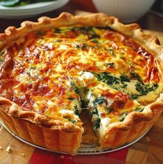 a quiche with cheese and spinach on a wooden table