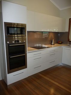 a modern kitchen with white cabinets and stainless steel appliances, including an oven and microwave