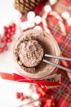 there is a spoon in a jar with some chocolate on it next to candy canes