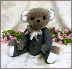 a brown teddy bear sitting next to pink flowers