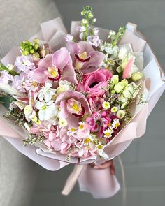 a bouquet of pink and white flowers in a paper wrapper on top of a chair