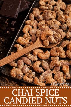 there is a spoon full of nuts on the table with chocolates in the background