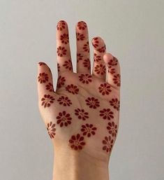 a woman's hand with red flowers painted on it and the palm of her hand