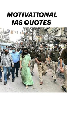 a woman in a green sari walking down the street with police officers behind her