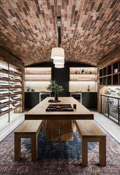 a wooden table sitting under a light fixture in a room with lots of shelves on the wall