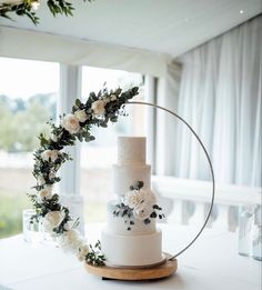 a wedding cake with white flowers and greenery on top is surrounded by a circular ring