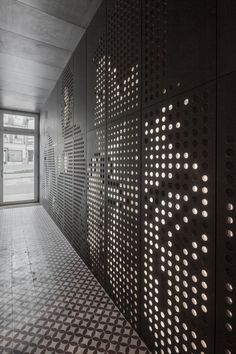 an empty hallway with black and white tiles on the walls, and a large window in the background