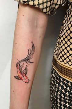 a woman's arm with a tattoo on it that has a goldfish in it