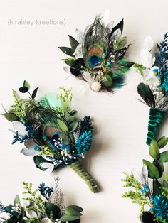 three bouquets with peacock feathers and flowers on white table top next to each other