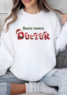 This Christmas-themed Sweatshirt features a design of 'Santa's favorite doctor' in a festive style, perfect for the holiday season. Made from 80% cotton and 20% polyester fabric, it offers a soft and luxurious feel, ideal for staying cozy and stylish during winter. The relaxed fit and ribbed collar, cuffs, and bottom hem provide comfort and flexibility, while the embroidery decoration on the left chest adds a special touch. An ideal gift for doctors or medical professionals who love the holiday spirit. Product features - 80% cotton, 20% polyester fabric for a soft feel - Relaxed fit and ribbed details for comfort - Embroidery decoration on left chest - Christmas-themed design for festive spirit - Ideal for doctors or medical professionals during the holiday season Care instructions - Machi Embroidery Decoration, Doctor Gift, Doctor Gifts, Modern Embroidery, Embroidered Tshirt, Casual Streetwear, Medical Professionals, Christmas Tshirts, Festival Fashion