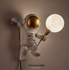 an astronaut is holding a light up in the shape of a ball and standing on one leg