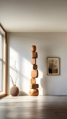 there is a tall stack of rocks next to a vase on the floor in front of a window