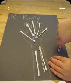 a child's hand writing on a piece of paper with white crayons