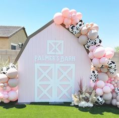 a pink barn with balloons and cow heads on it