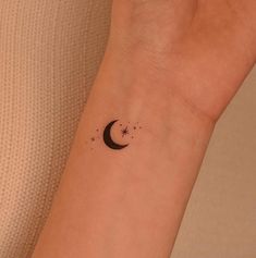 a small tattoo on the wrist of a woman's arm with a crescent moon and stars