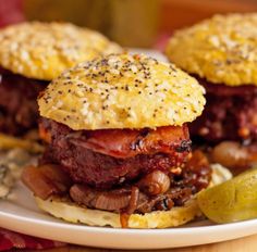 two hamburgers with meat, onions and pickles on a plate